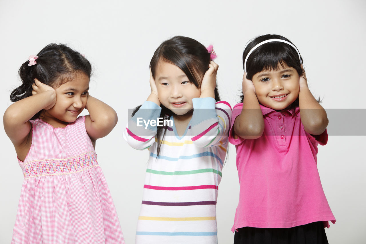 Cute girls covering ears against white background