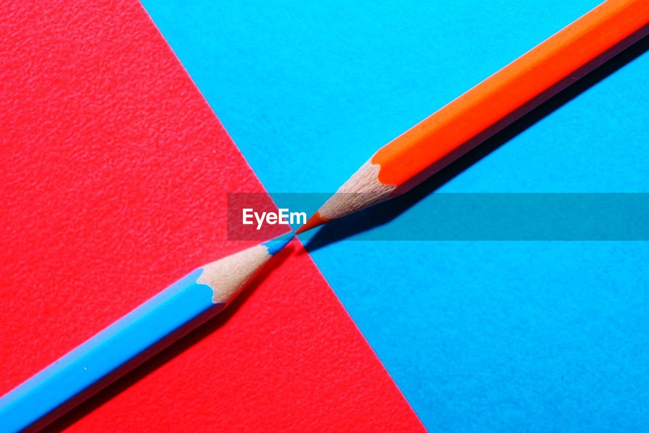 HIGH ANGLE VIEW OF MULTI COLORED PENCILS ON BLUE TABLE