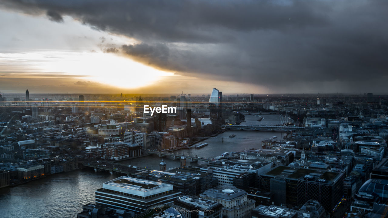 High angle view of river in city against cloudy sky during sunset