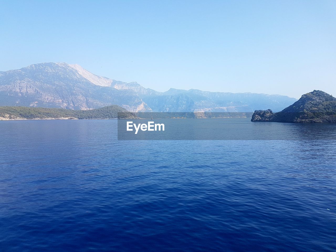 SCENIC VIEW OF SEA AND MOUNTAINS AGAINST CLEAR SKY