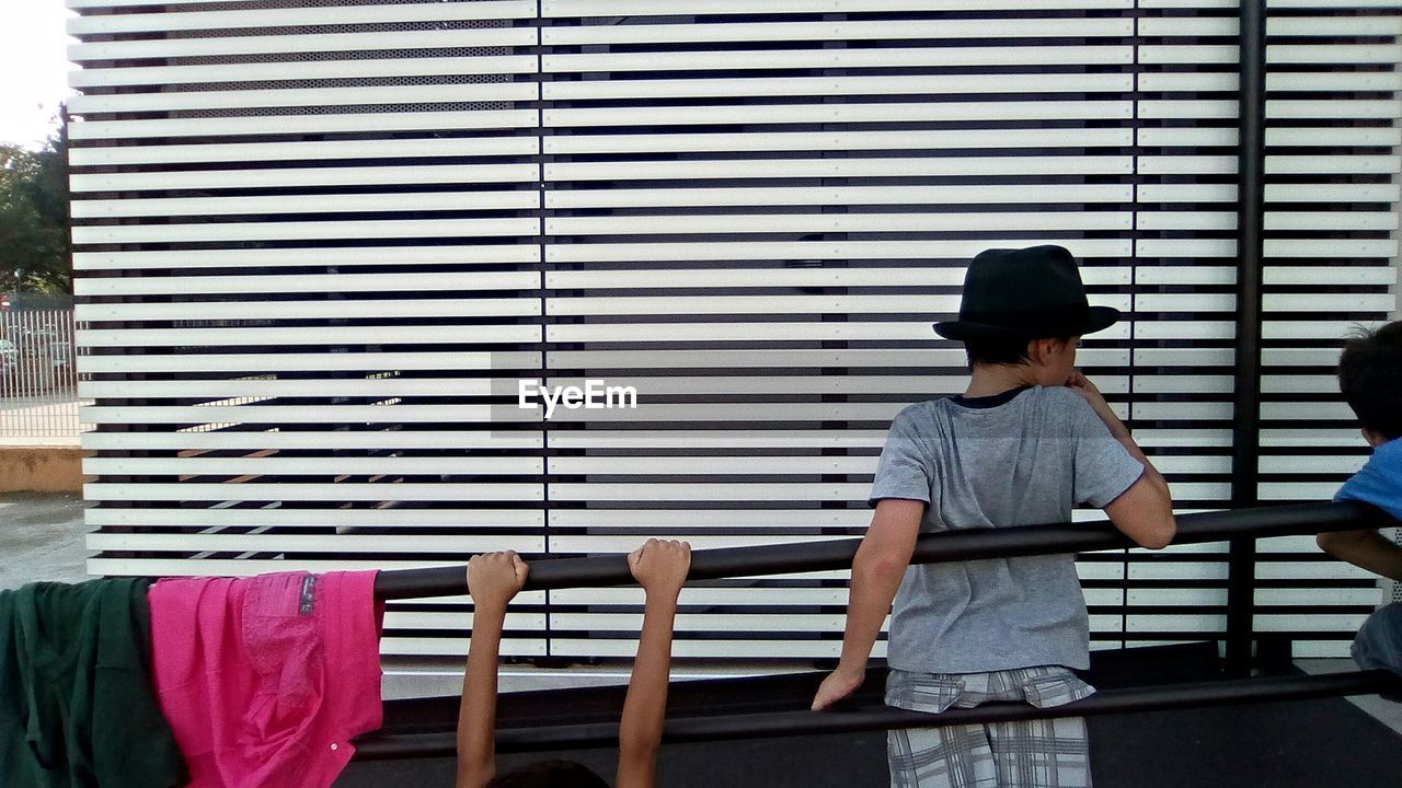 Children at railing in front of patterned wall