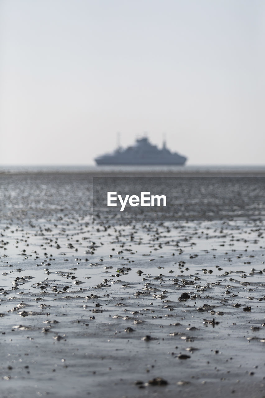 Denmark, romo, mud flat during low tide with ferry in distant background