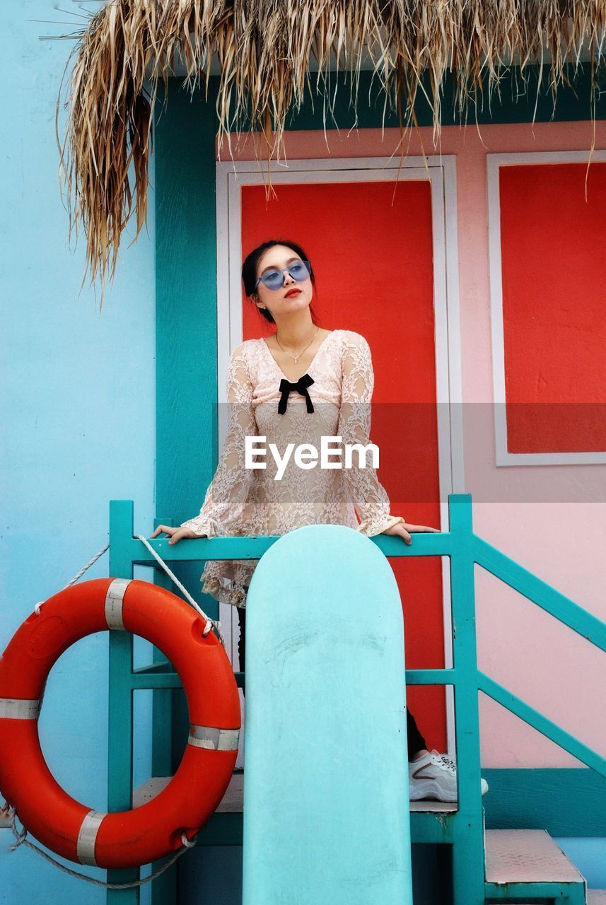 Young woman standing in front of a colorful beach hut