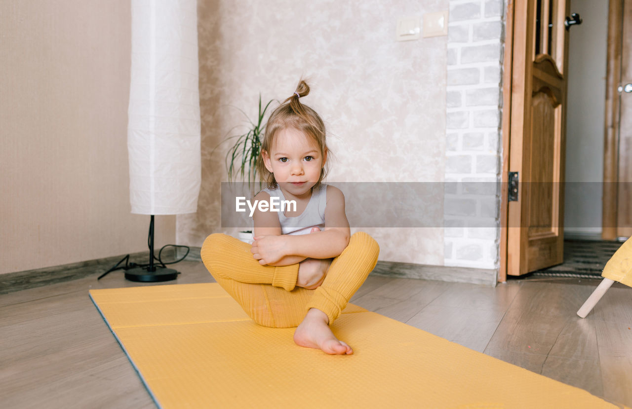 Portrait of smiling girl sitting on wooden floor at home