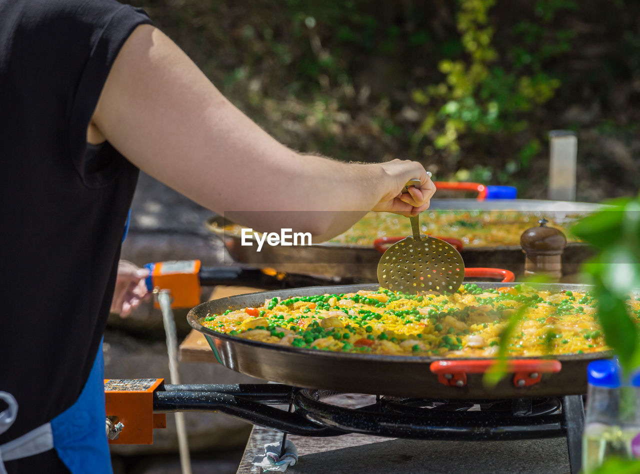 Midsection of woman preparing food on stove burner outdoors