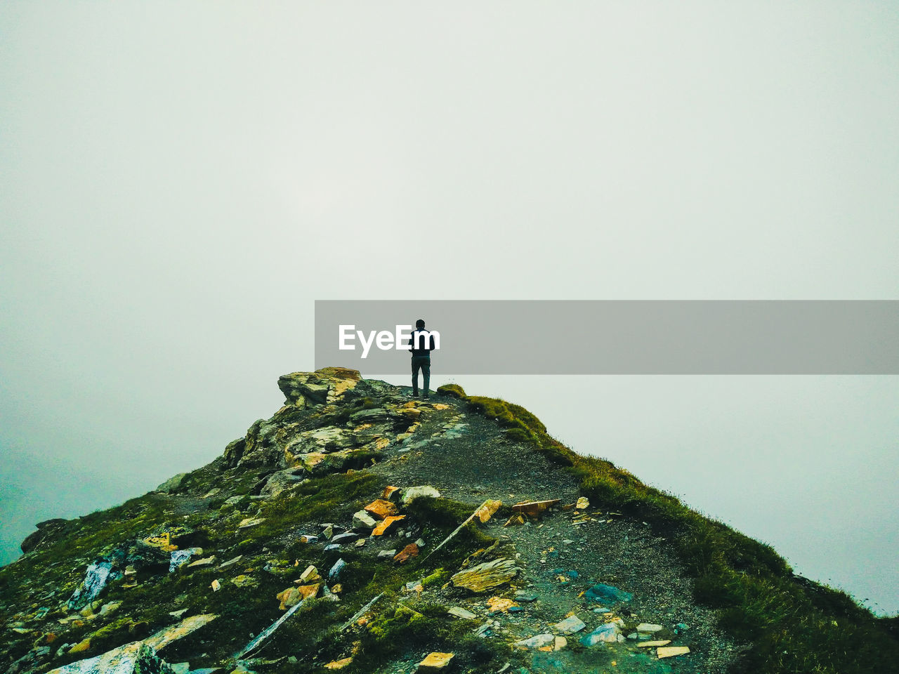 Rear view of man standing on mountain against sky
