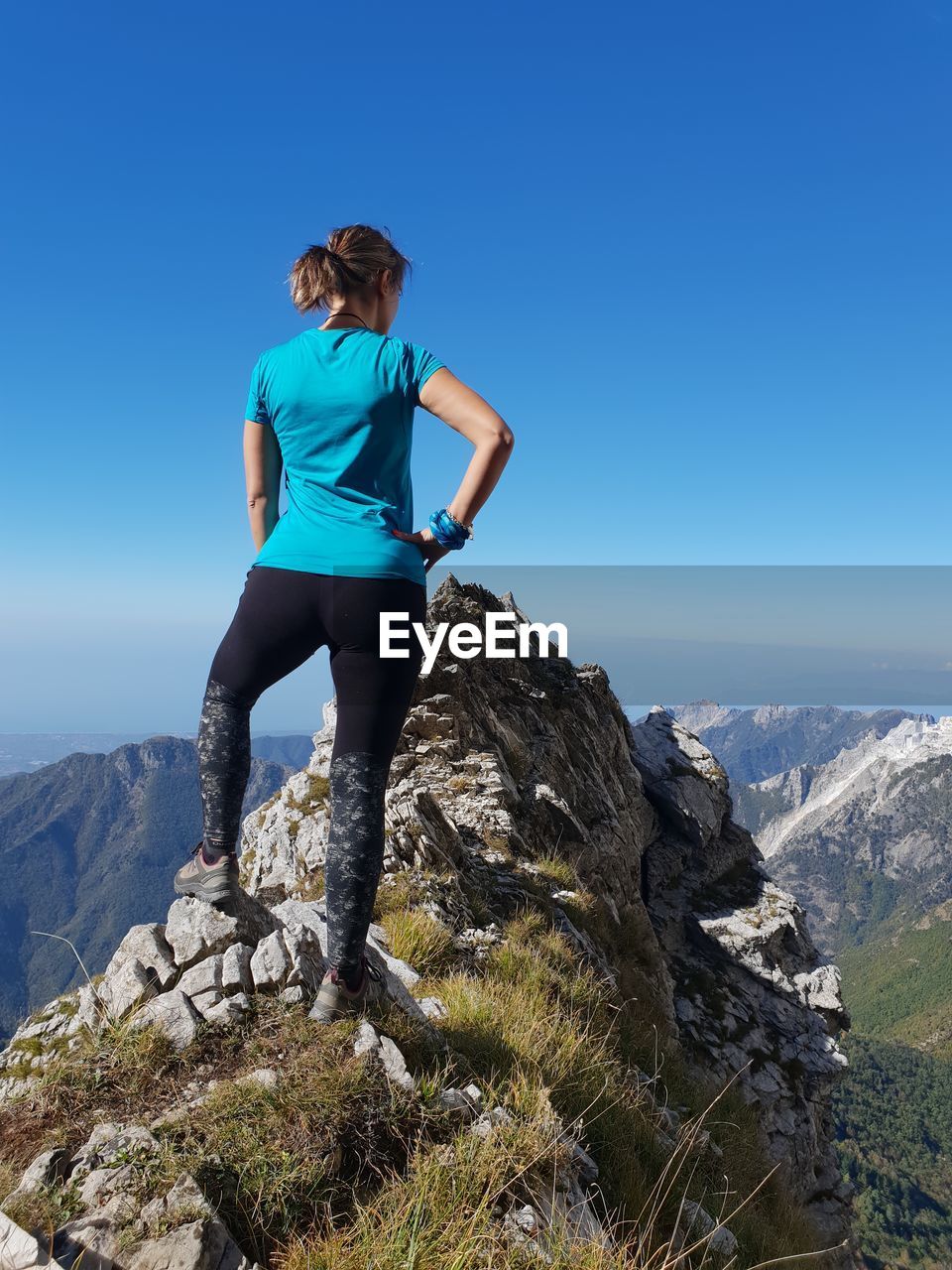 Full length of woman standing on rock against clear sky