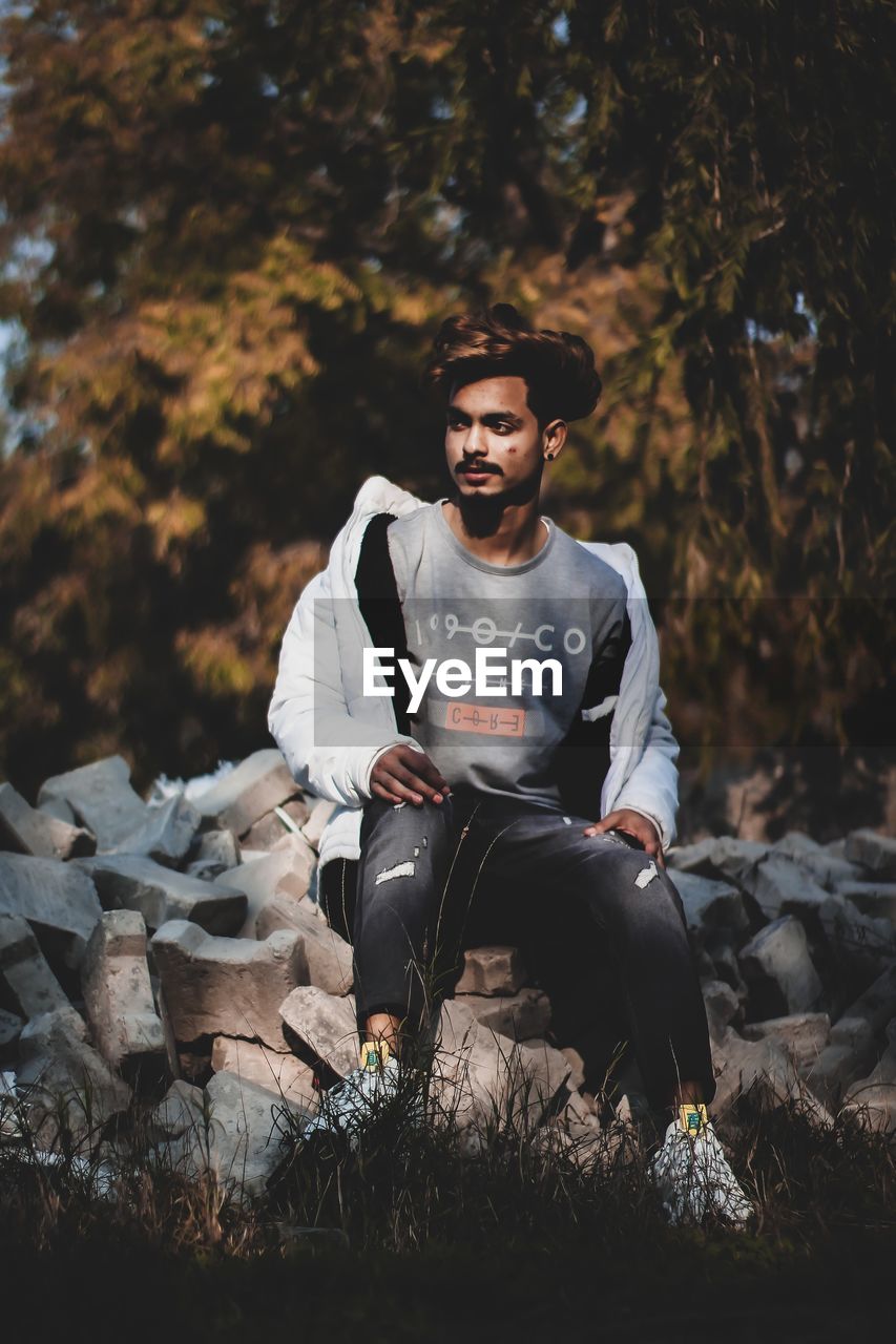 YOUNG MAN LOOKING AWAY ON ROCK