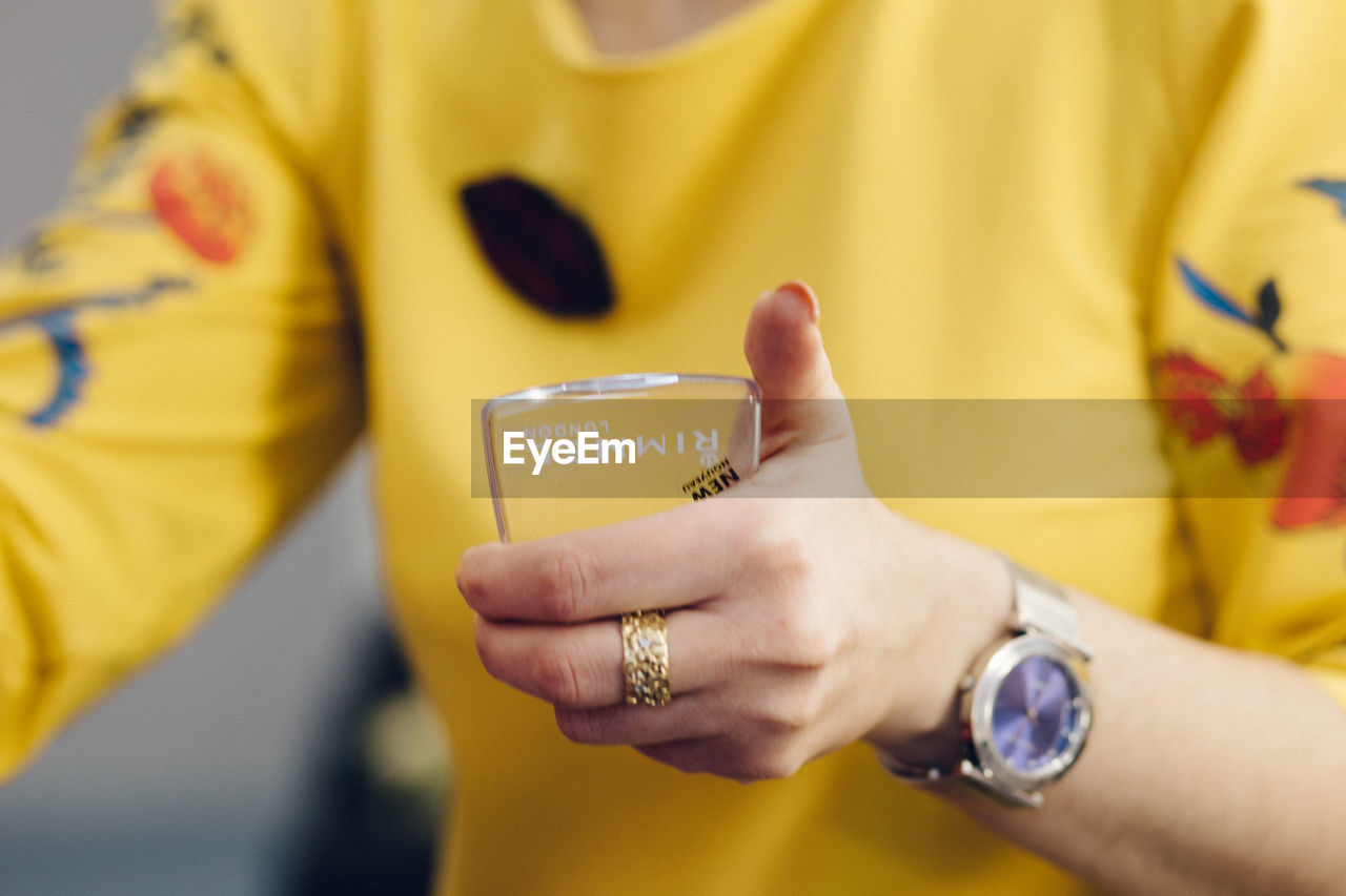 CLOSE-UP OF MAN HOLDING YELLOW TEXT ON PAPER