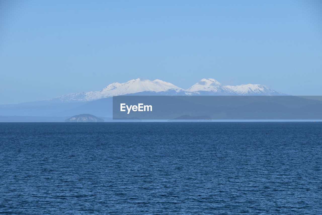 Scenic view of sea and snowcapped mountains against sky