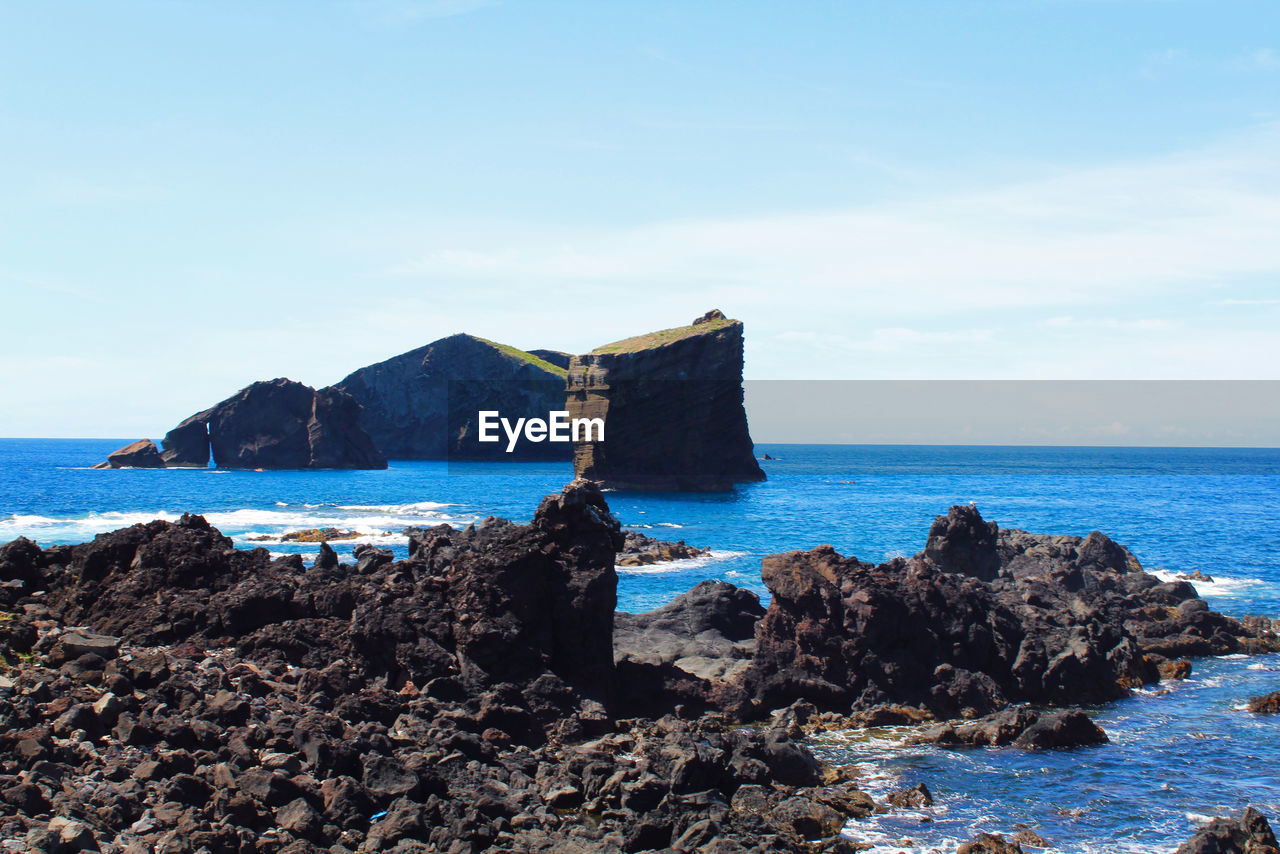 SCENIC VIEW OF ROCKS ON SHORE AGAINST SKY