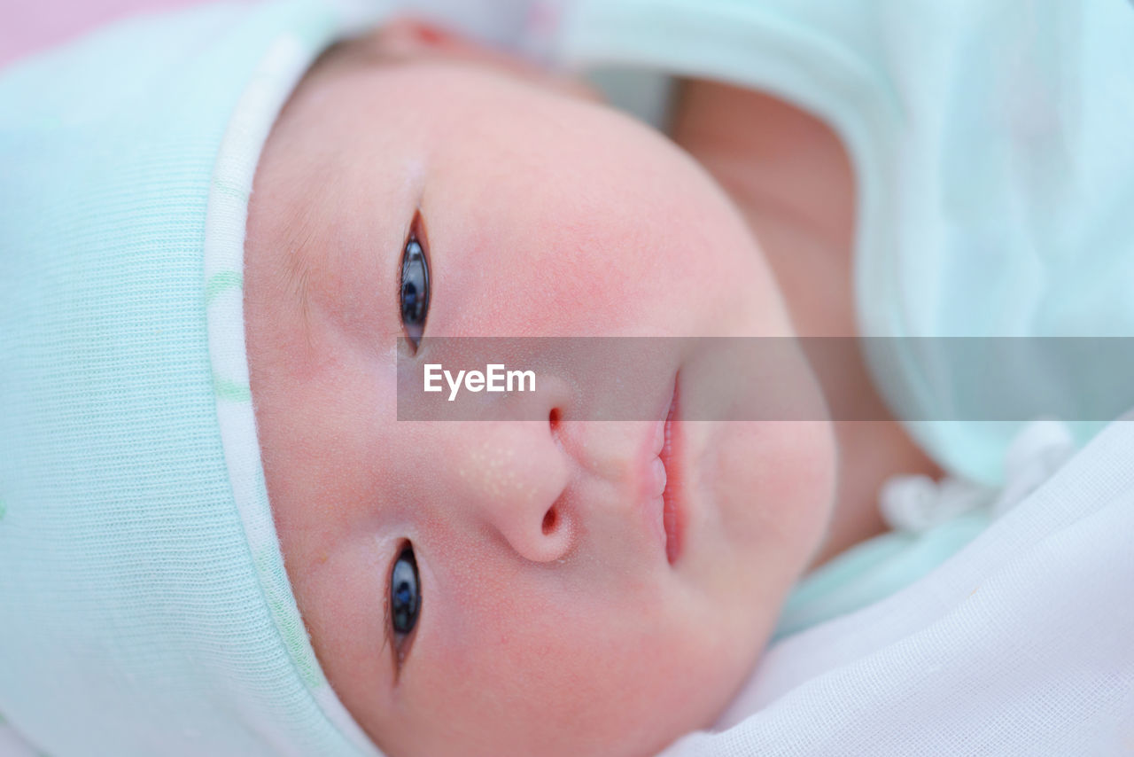 close-up of cute baby girl lying on bed at home