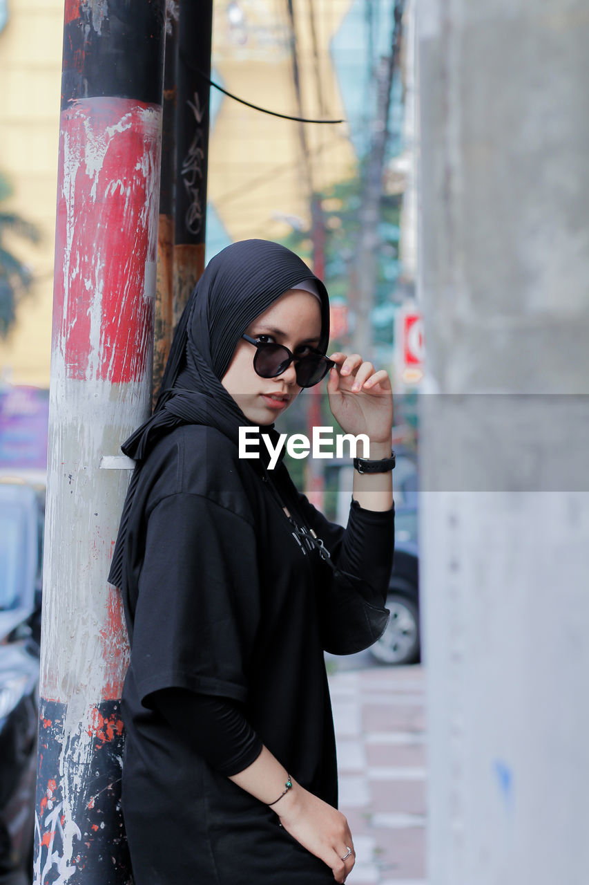 Portrait of young woman wearing sunglasses standing outdoors