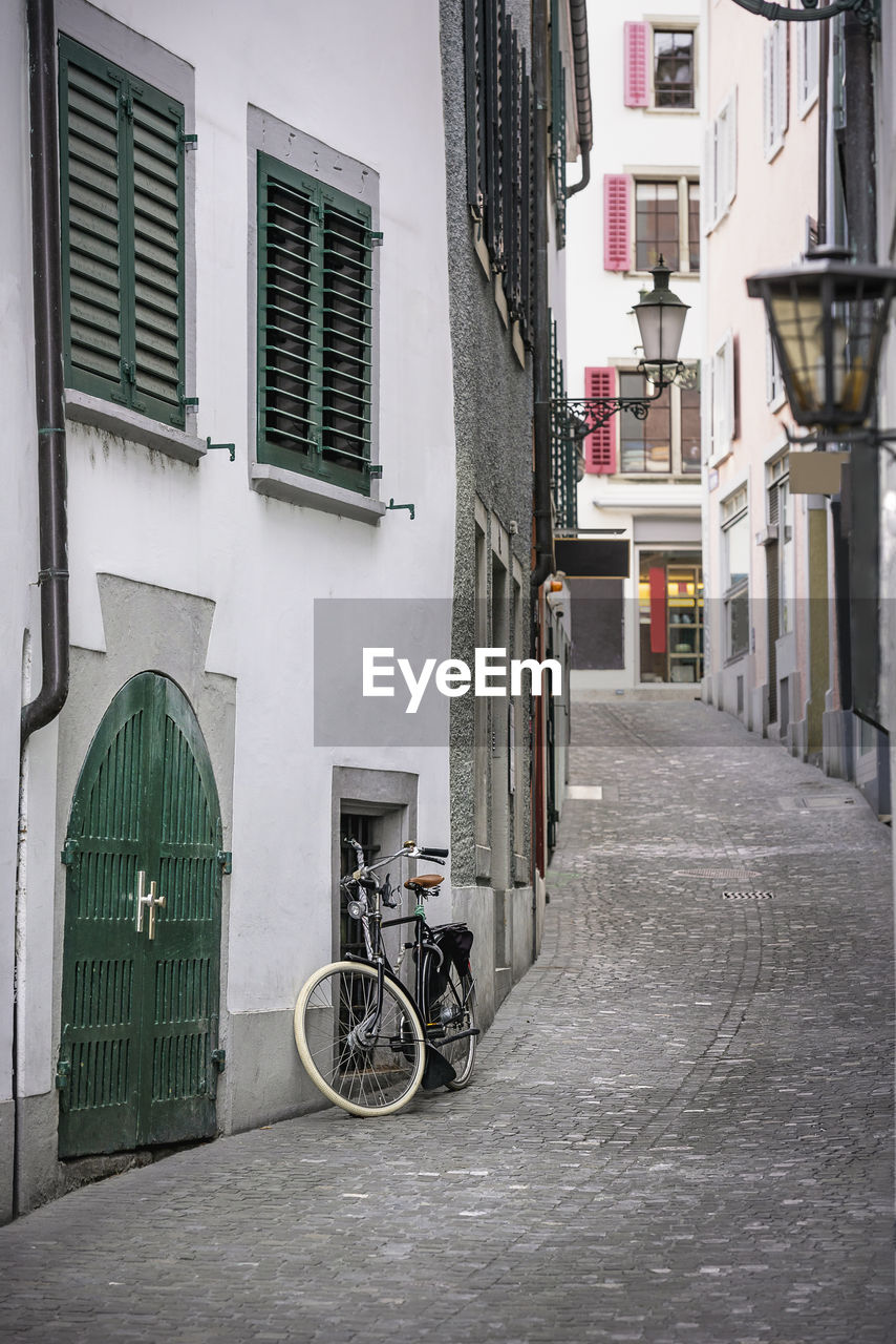 Bicycles parked on street amidst buildings