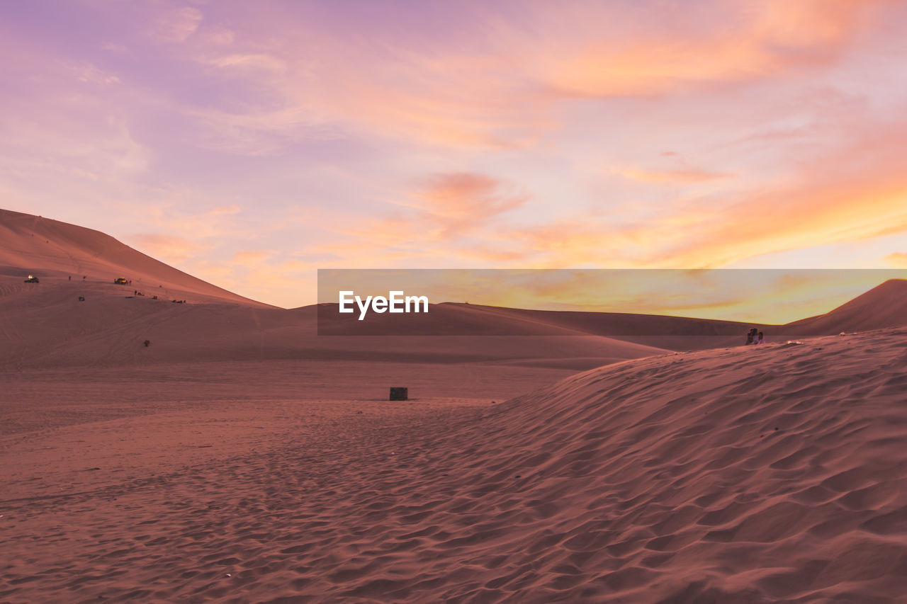 Scenic view of desert against cloudy sky