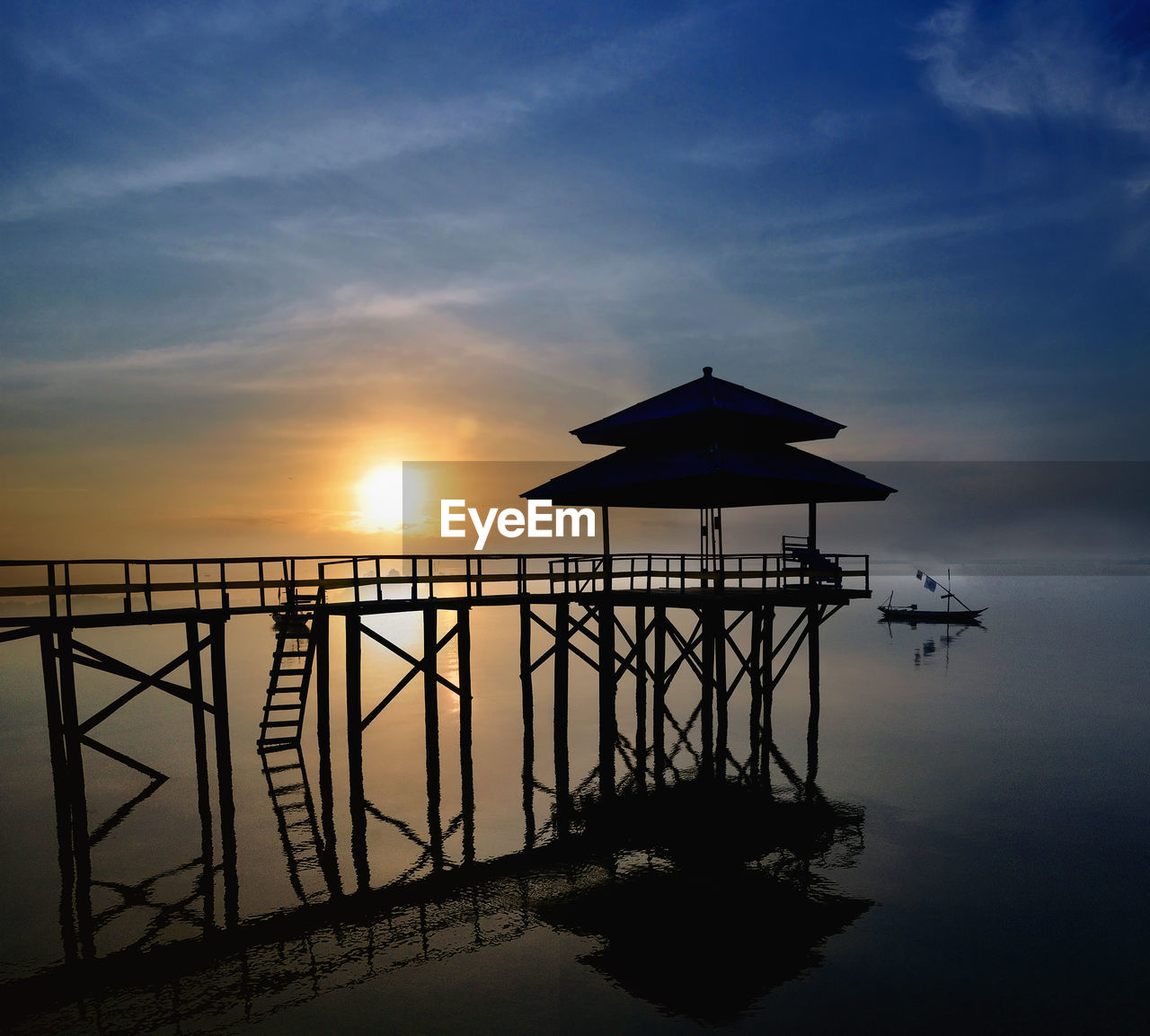 SILHOUETTE BUILT STRUCTURE IN SEA AGAINST SKY DURING SUNSET