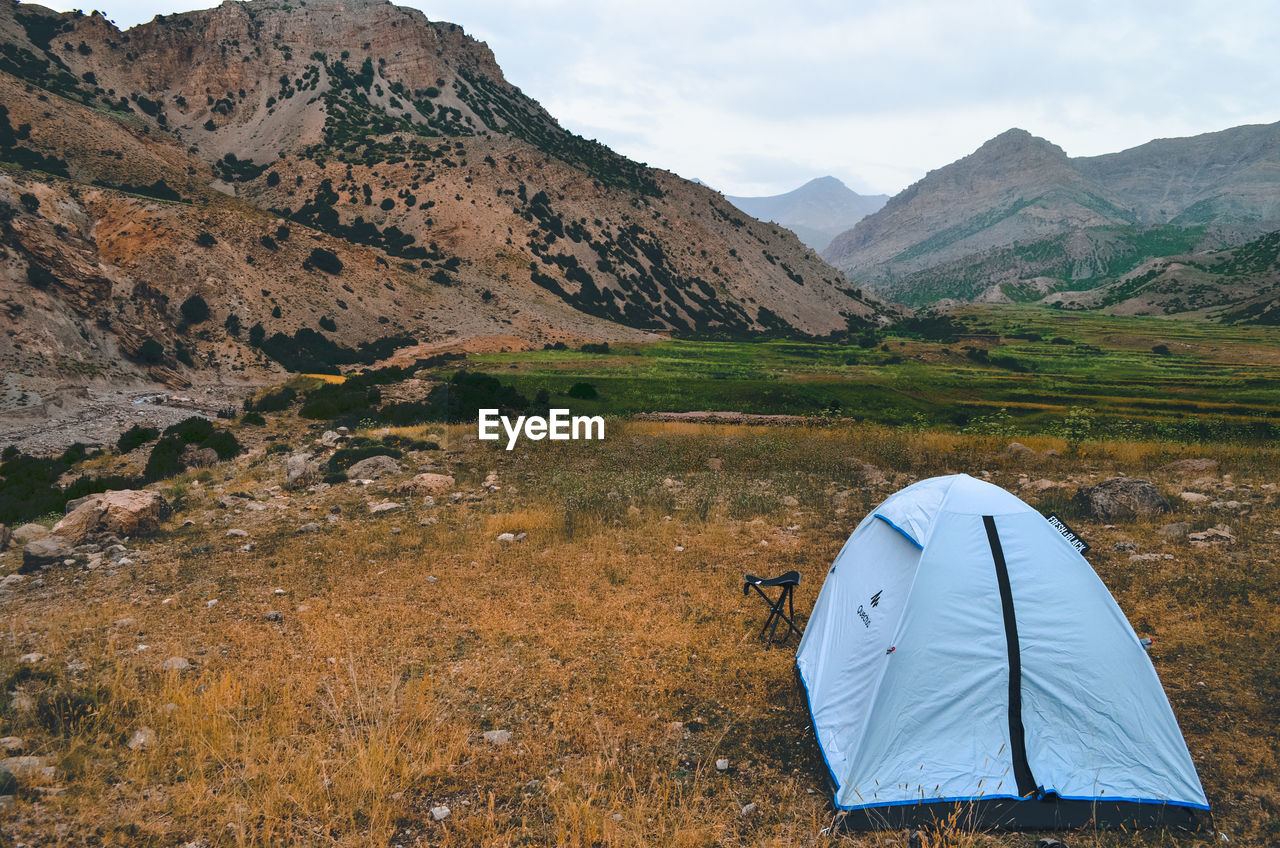 TENT ON FIELD AGAINST MOUNTAINS