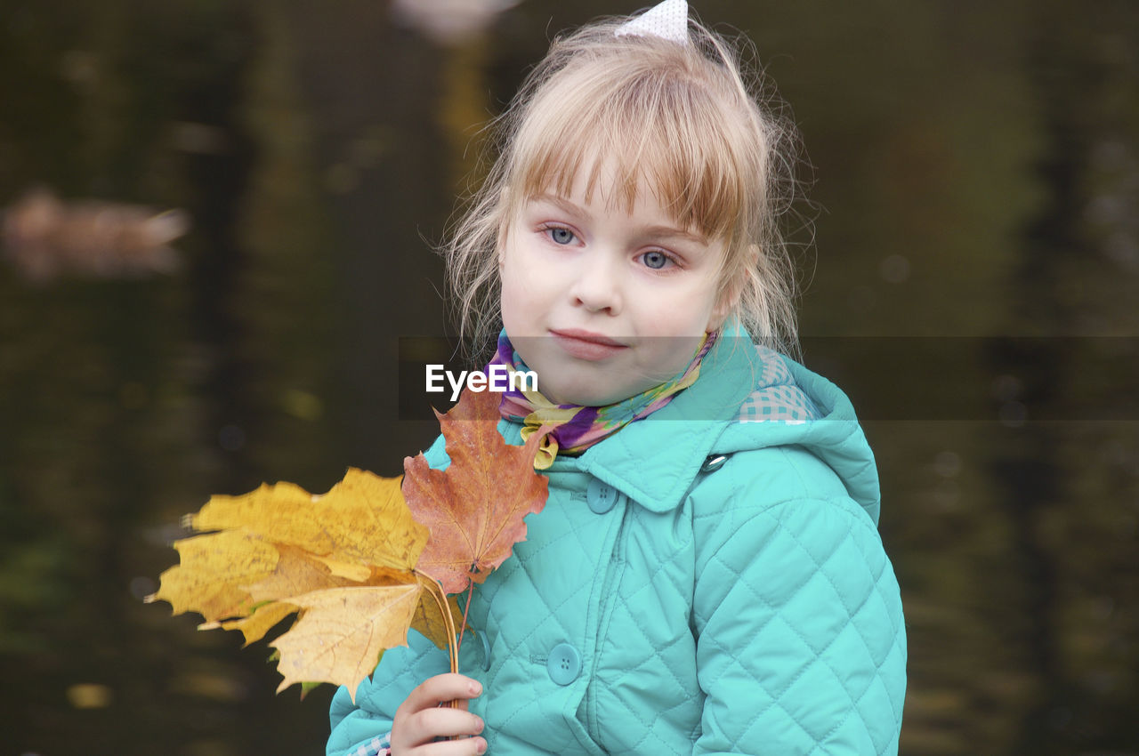 Cute girl holding autumn leaves at park