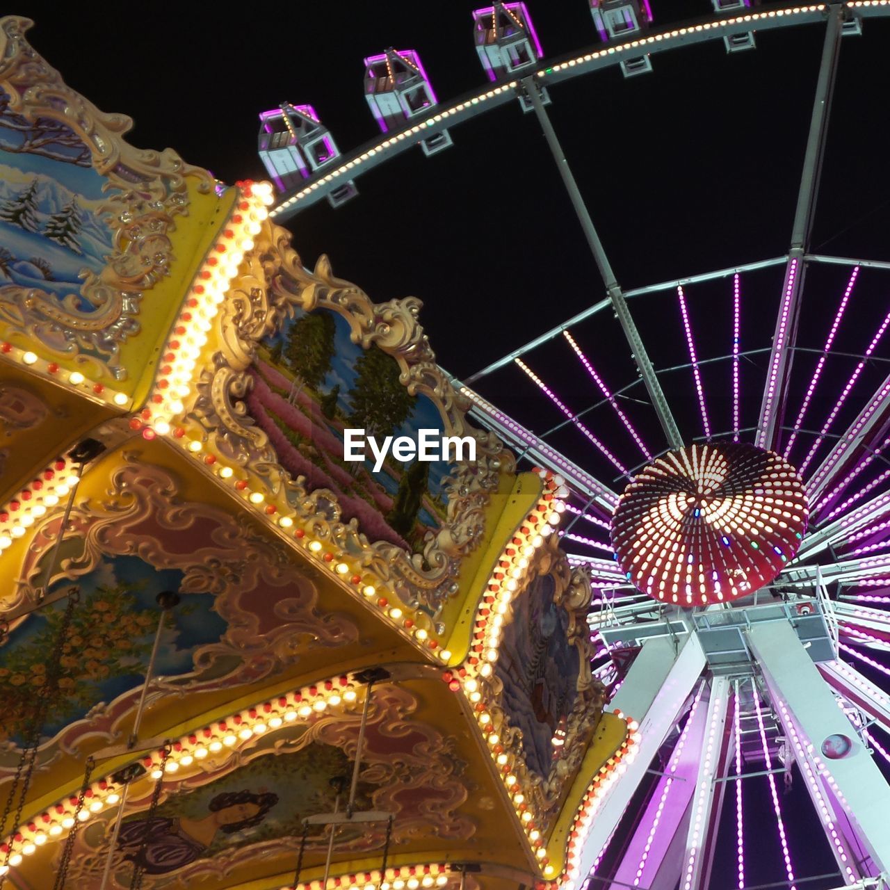 Illuminated carousel ride and ferris wheel at night 