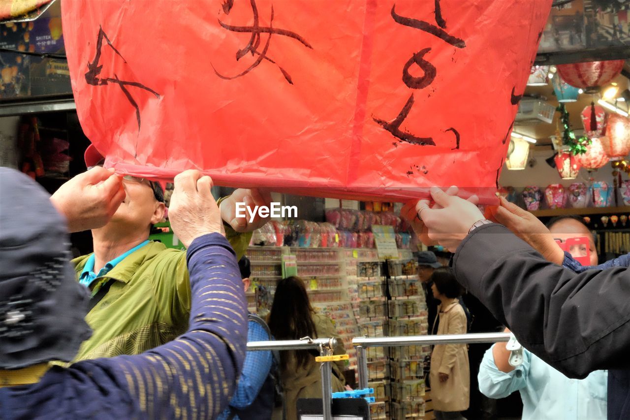 REAR VIEW OF PEOPLE WORKING AT MARKET STALL