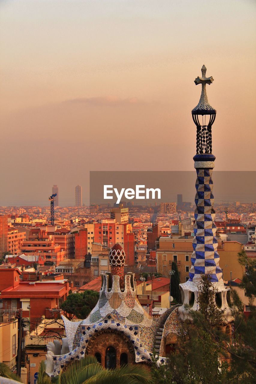 High angle view of art nouveau church tower against cityscape at sunset