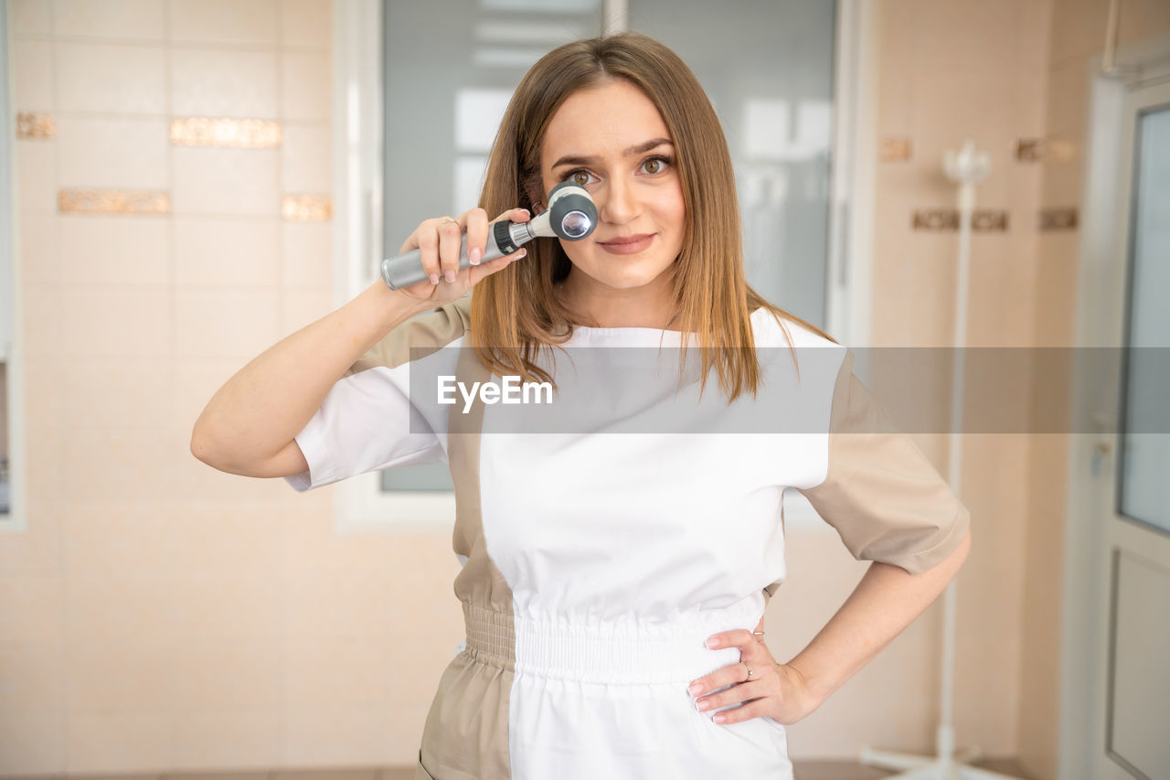 portrait of young woman drinking water while standing at home