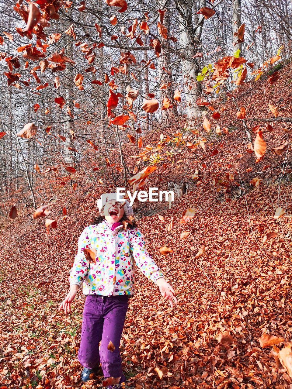 Happy girl playing with leaves in autumn