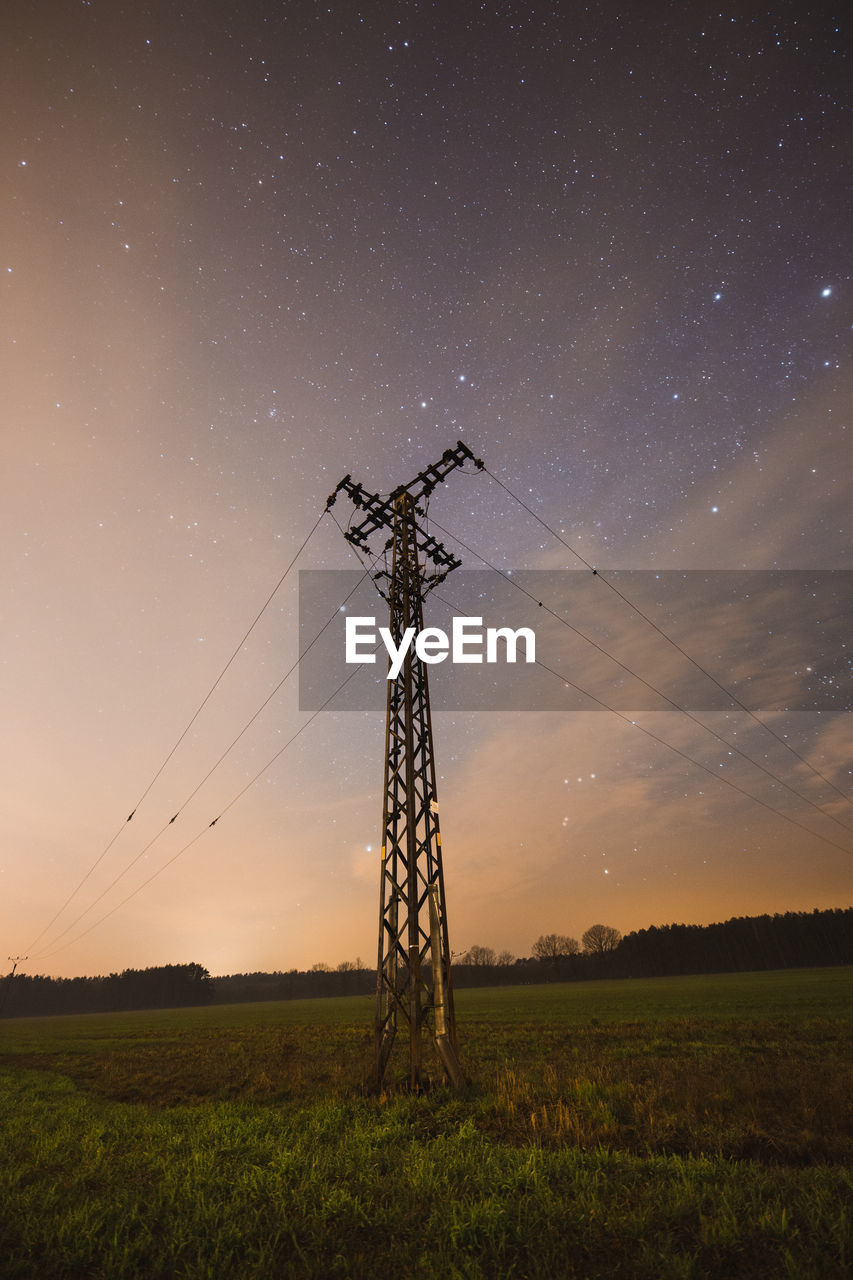 Low angle view of electricity pylon on land against sky at night