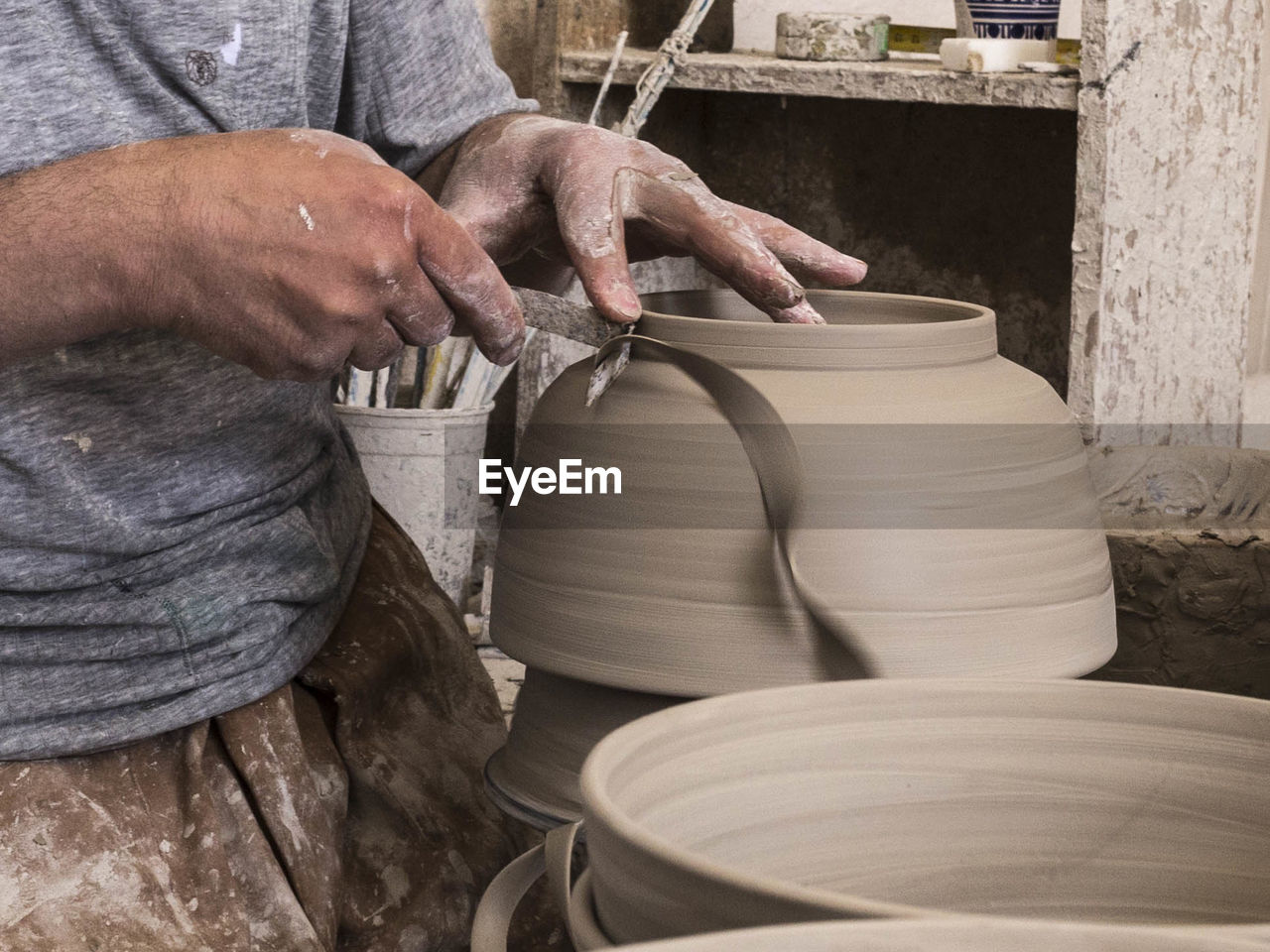 Midsection of man making pottery at workshop