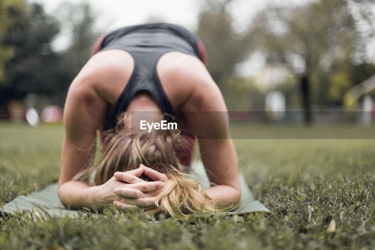 Woman practicing headstand on grassy field