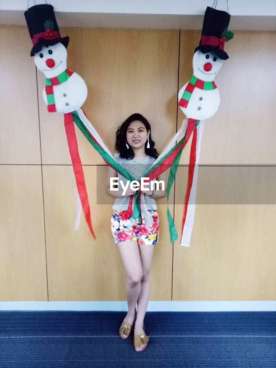 Portrait of smiling young woman with decorations against wall