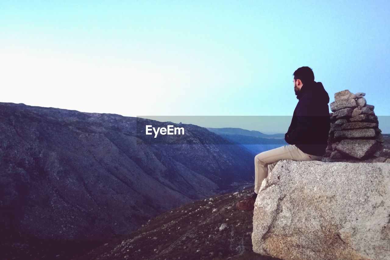 Side view of man sitting on cliff