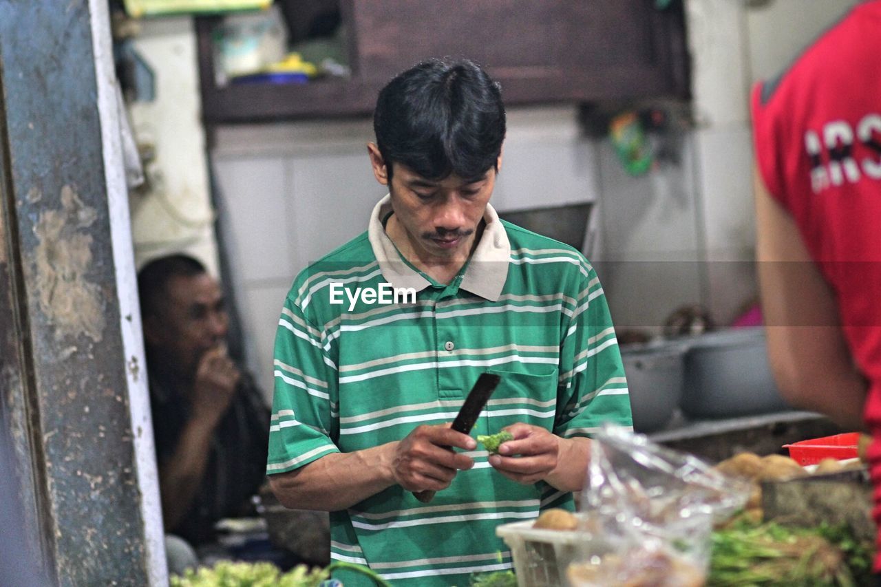 Chef cutting vegetable while standing in commercial kitchen