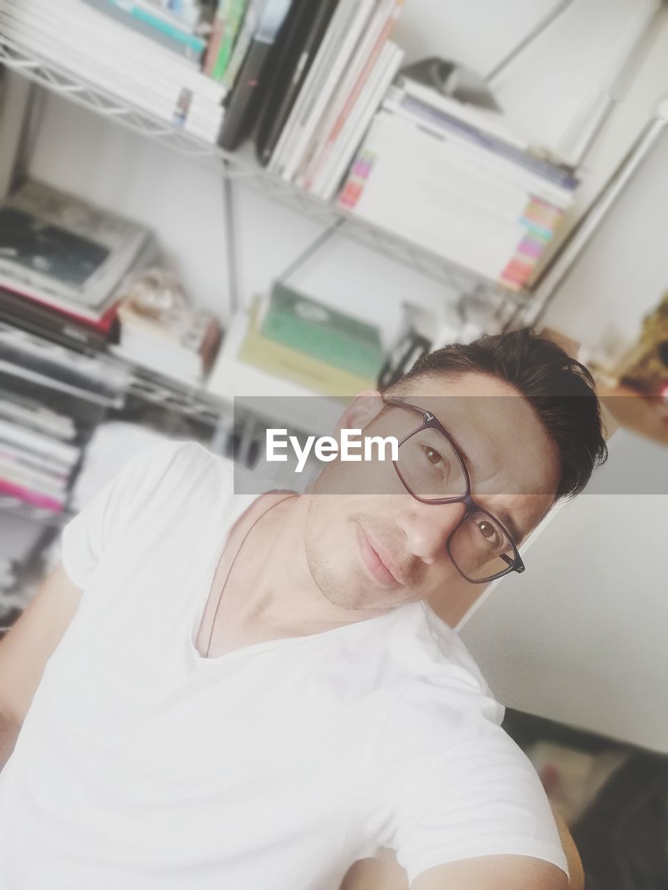 PORTRAIT OF A YOUNG MAN SITTING IN OFFICE