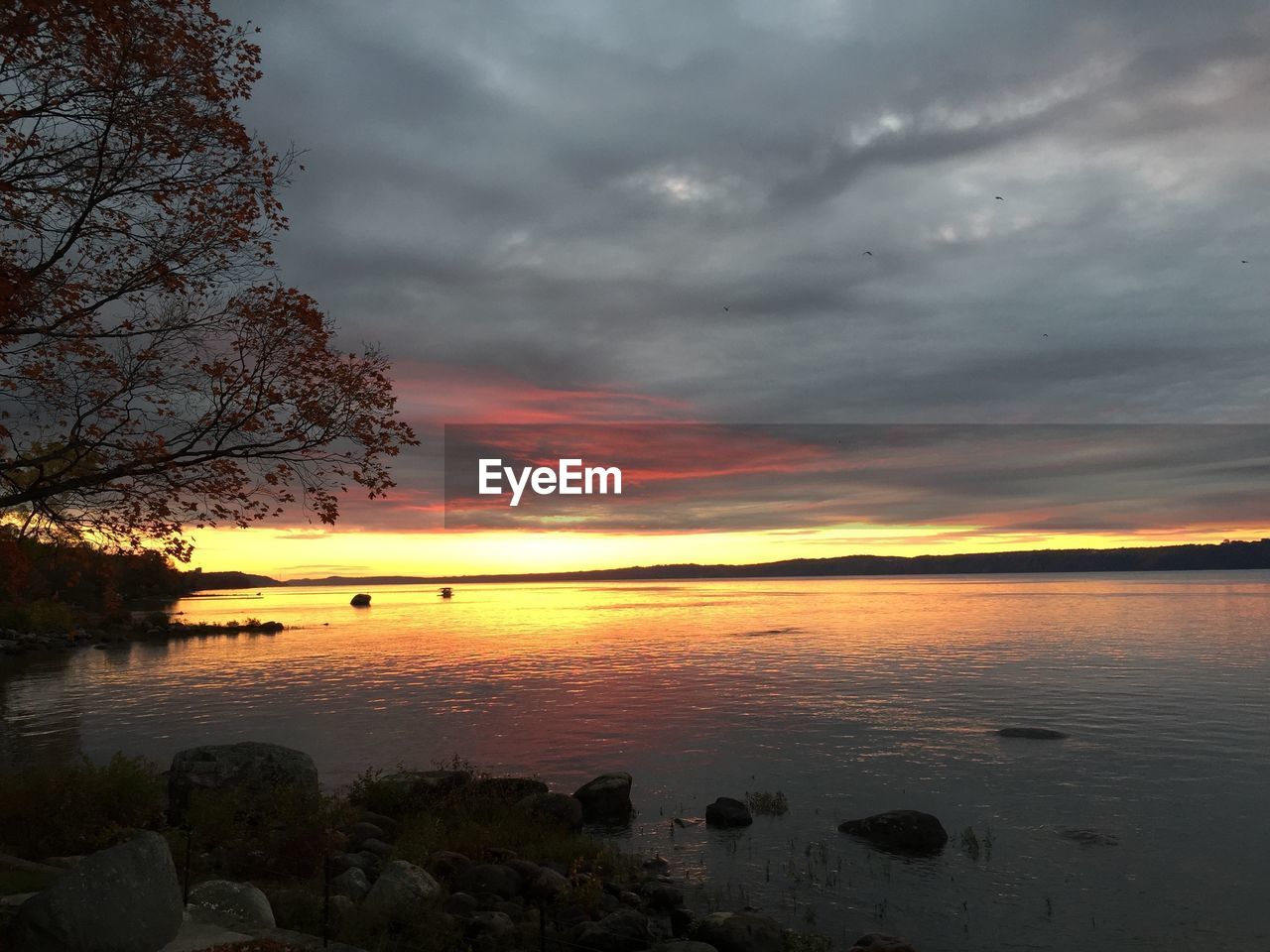 Scenic view of lake against cloudy sky during sunset