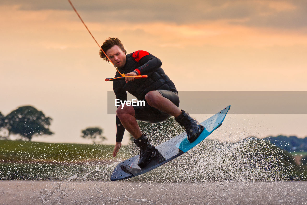 Full length of man wakeboarding against sky
