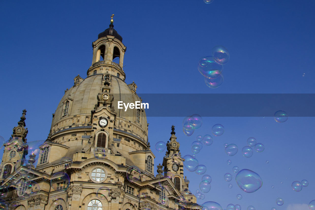 Low angle view of bubbles by church against clear blue sky