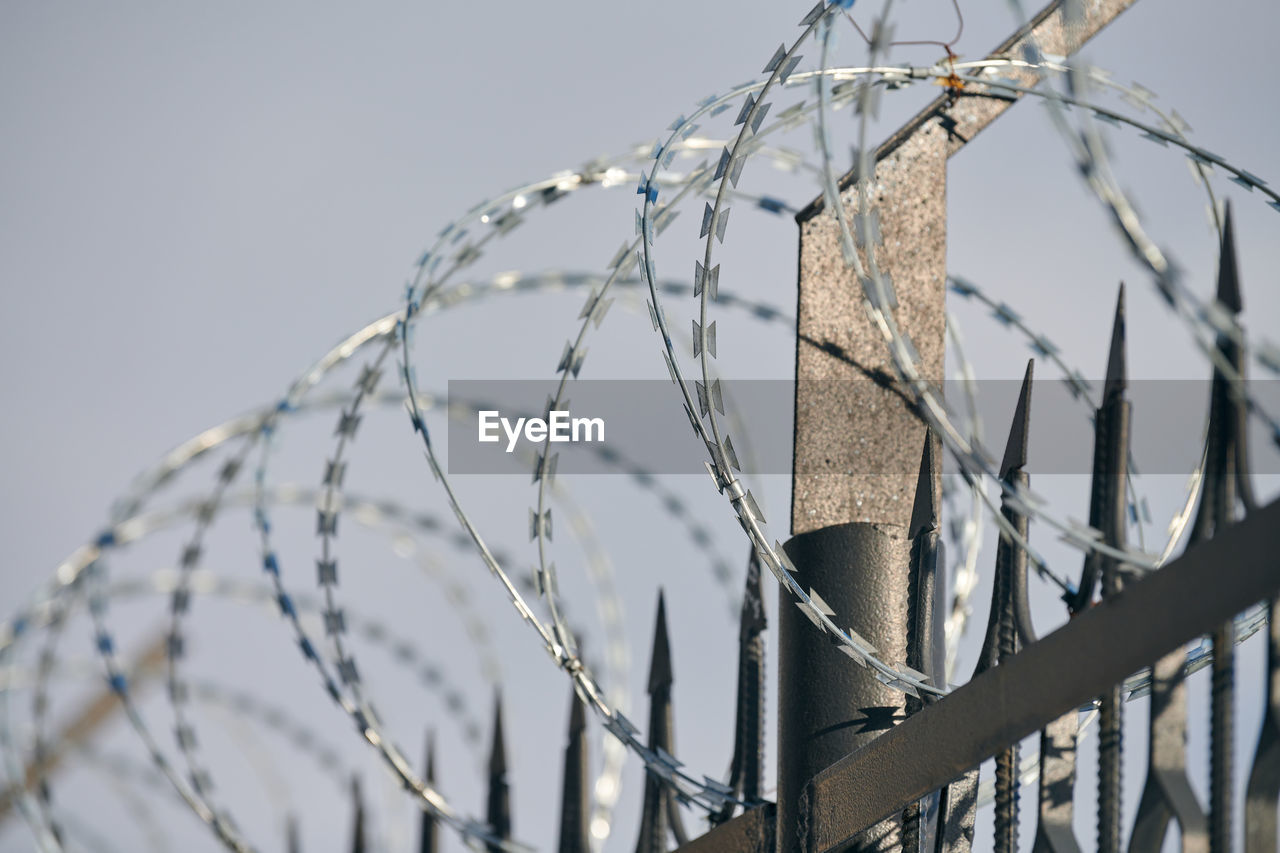 Barbed wire on fence, steel grating fence, metal fence wire. coiled razor wire with sharp barbs