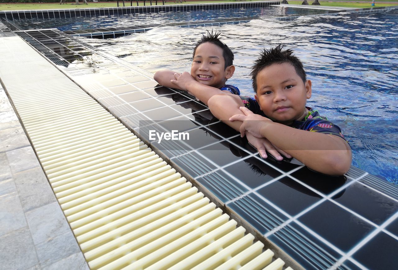 Portrait of smiling brothers in swimming pool