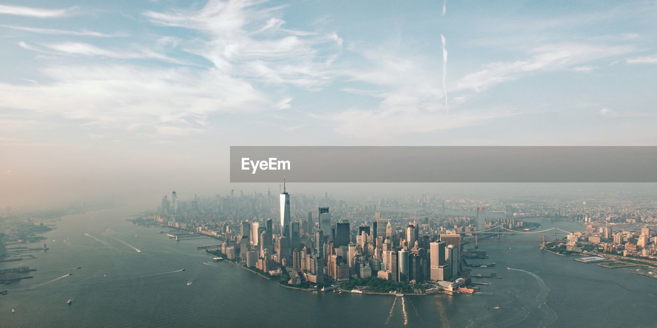 Aerial view of city buildings and sea against sky