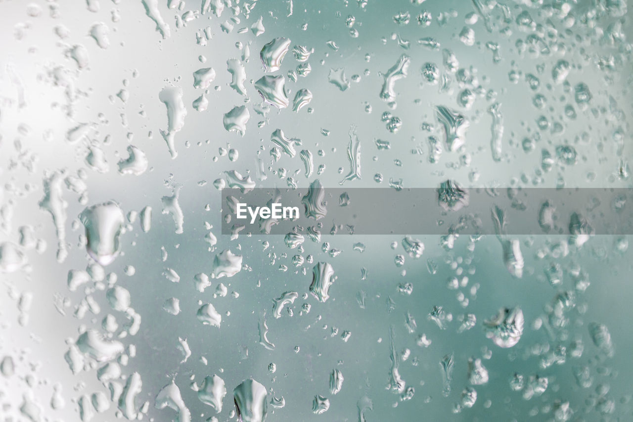 Raindrops on a windowpane with blue background