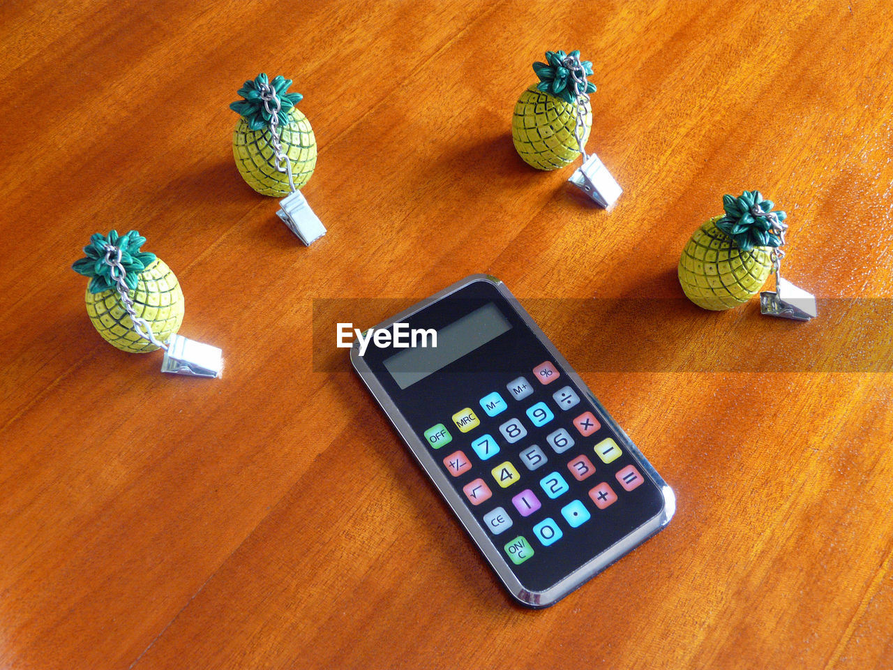 High angle view of calculator with pineapple figurines on wooden table