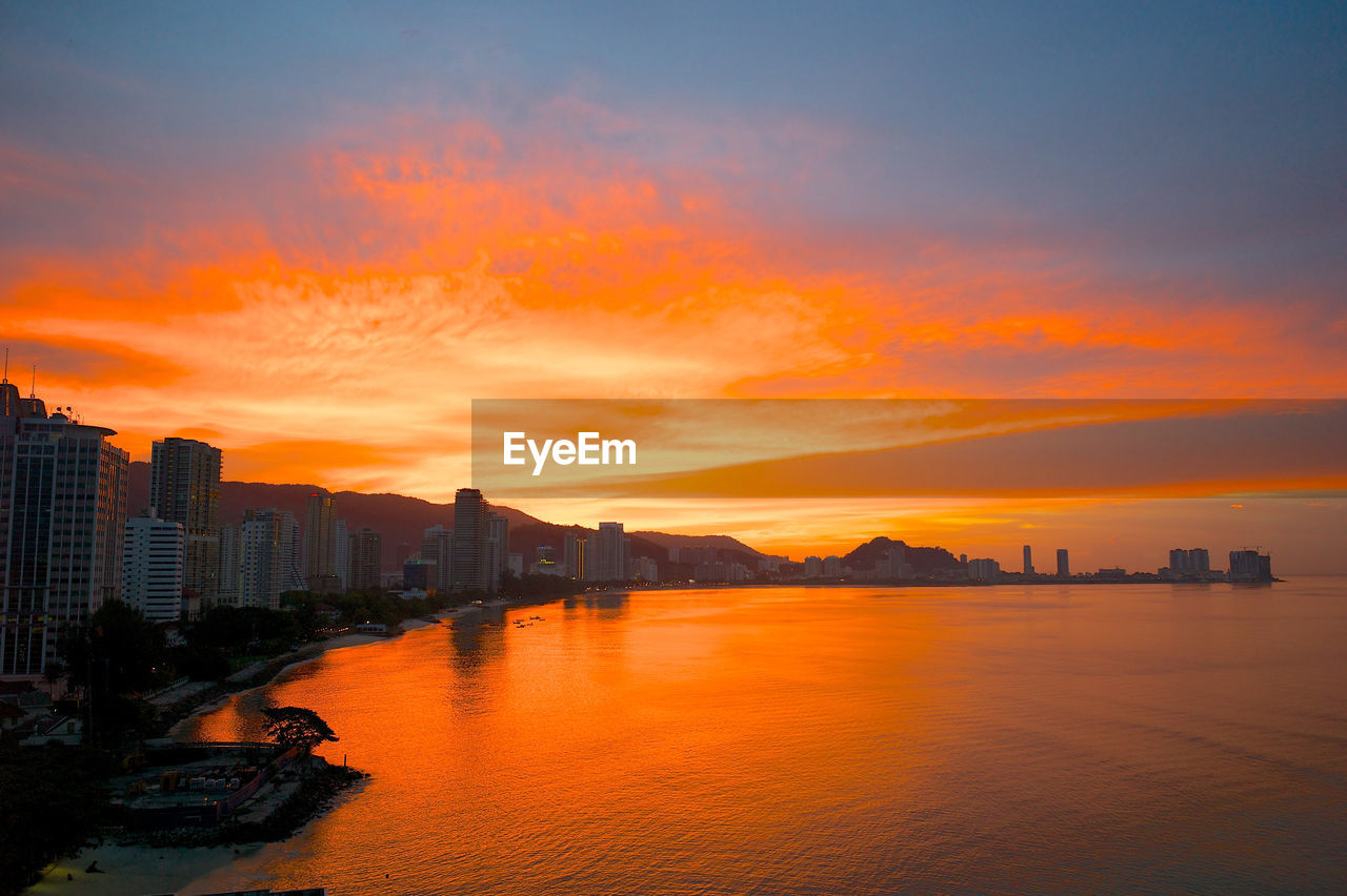 Scenic view of sea and buildings against sky during sunset