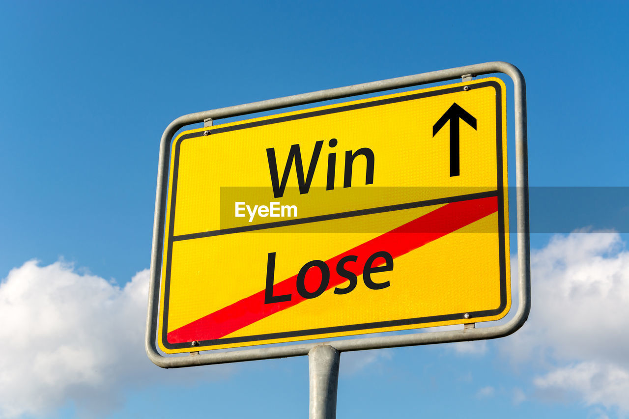 Low angle view of road sign against blue sky