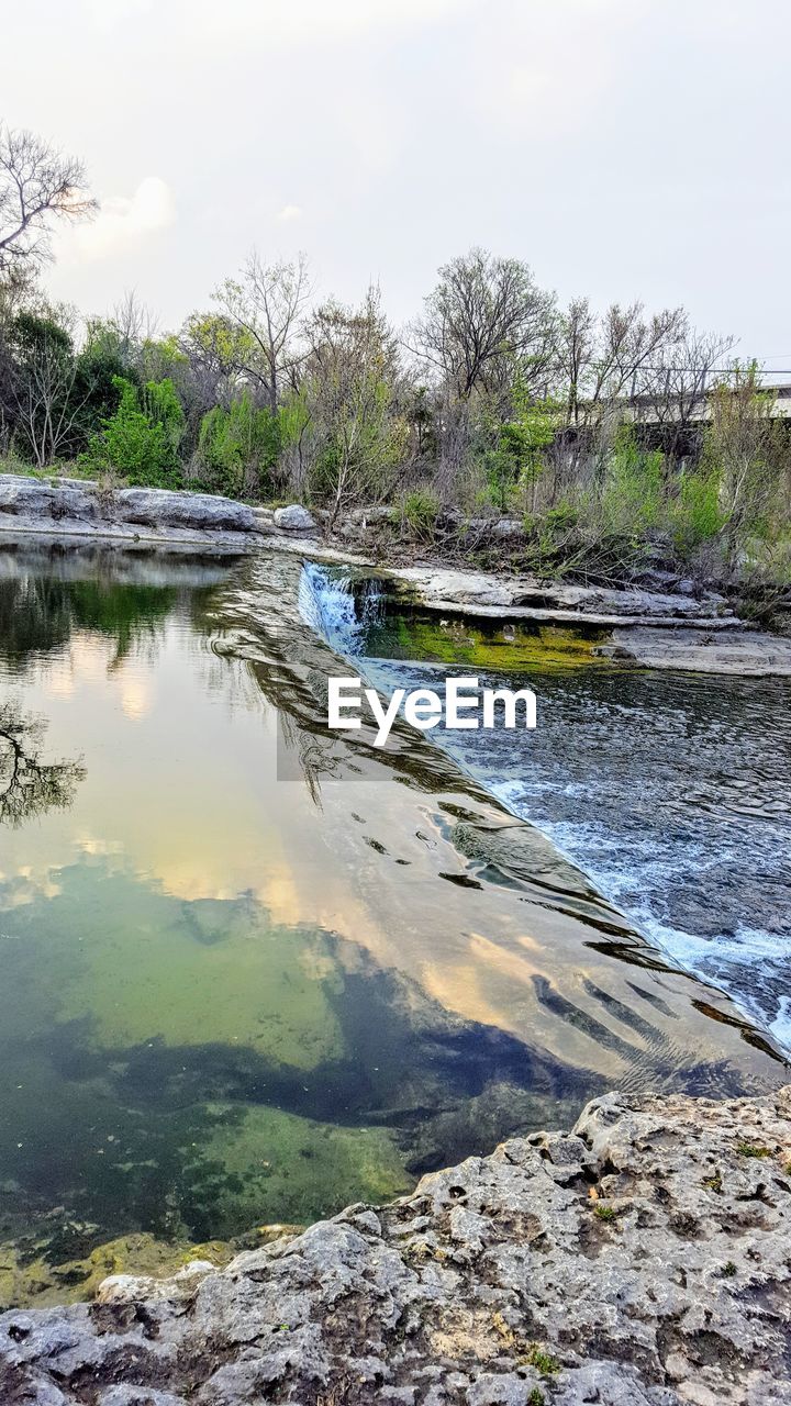 REFLECTION OF TREES IN RIVER AGAINST SKY