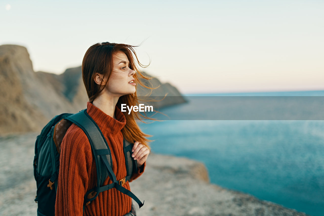 Young woman looking at sea against sky