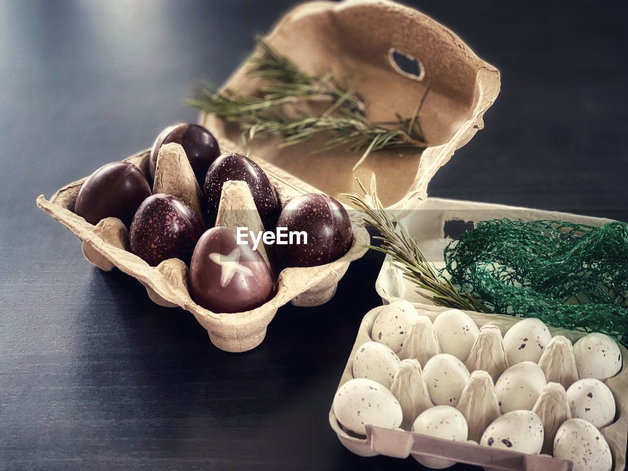 Close-up of chocolate and praline easter eggs in cardboard cartons on table.