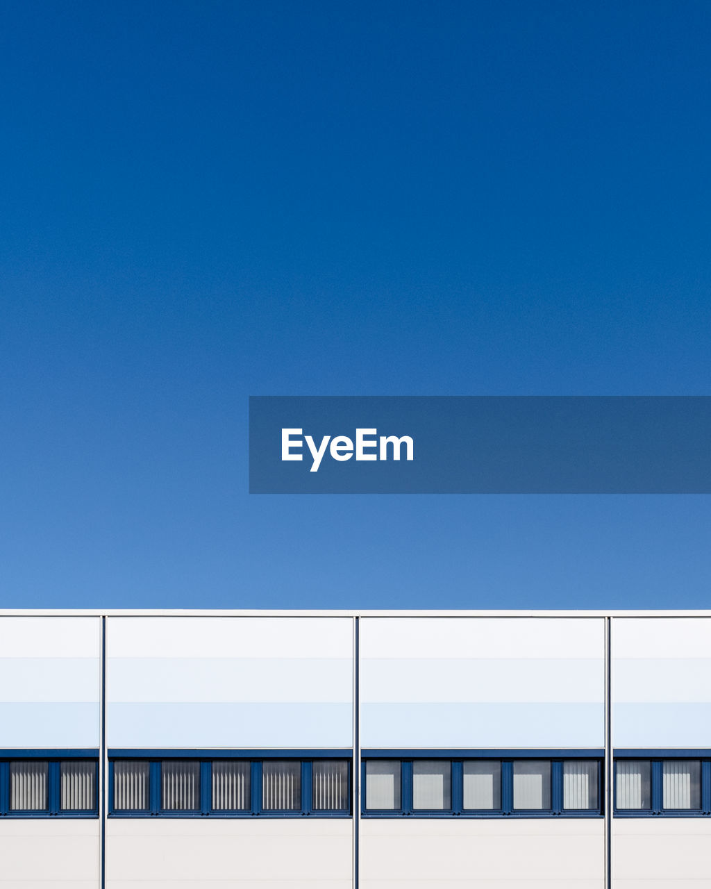 Low angle view of modern building against clear blue sky