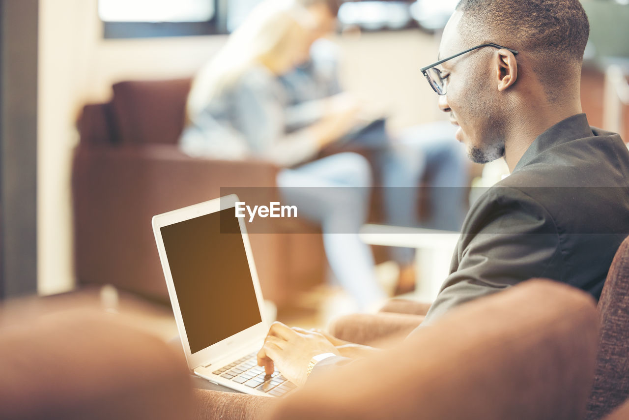 A black man works on a tablet computer in the hotel lobby.