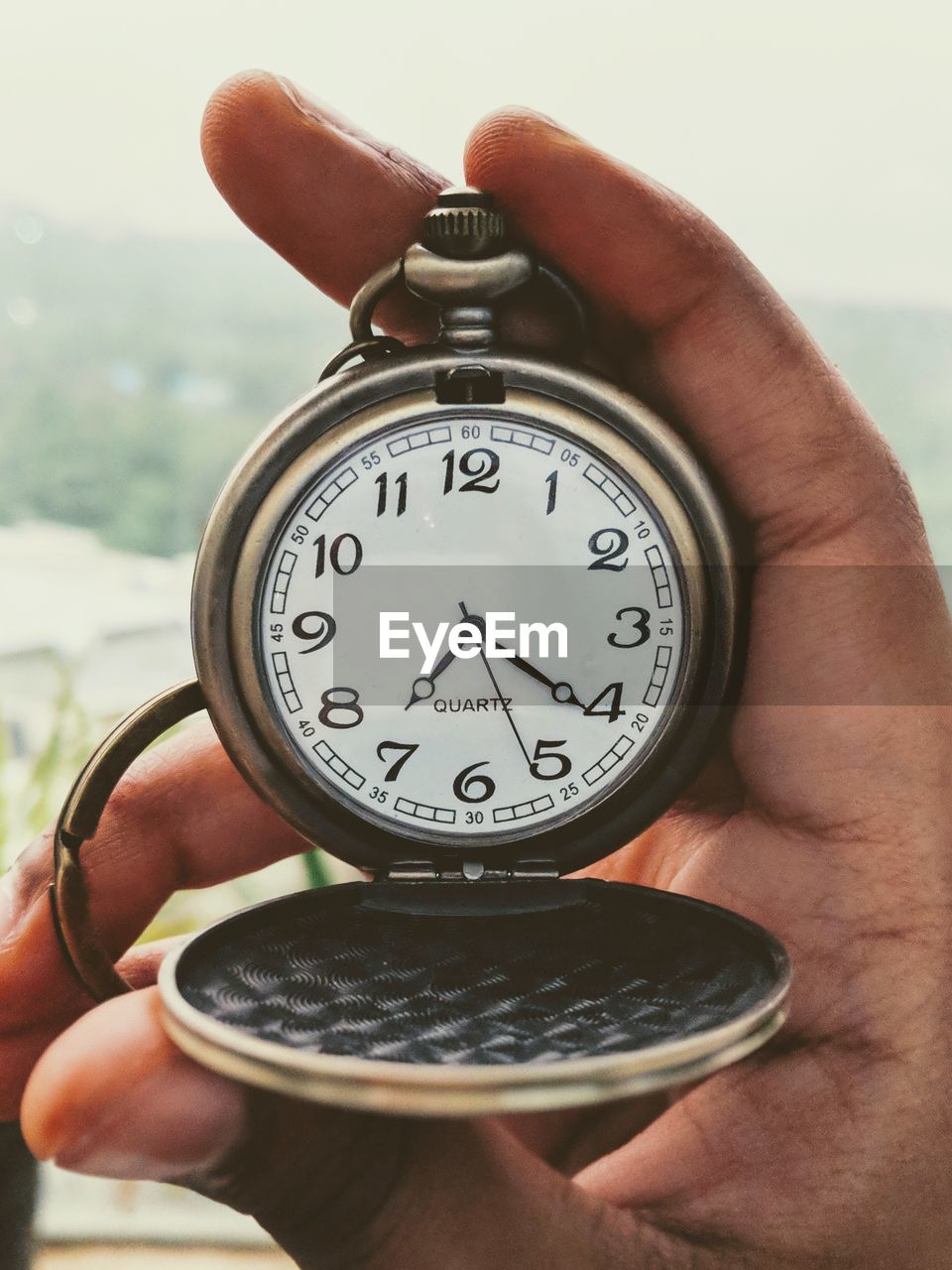 CLOSE-UP OF PERSON HAND HOLDING CLOCK